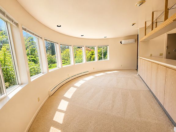 Sun-filled living room overlooking acreage gardens. This view is back towards the entry. New mini-split HP, new blinds, freshly cleaned carpets.