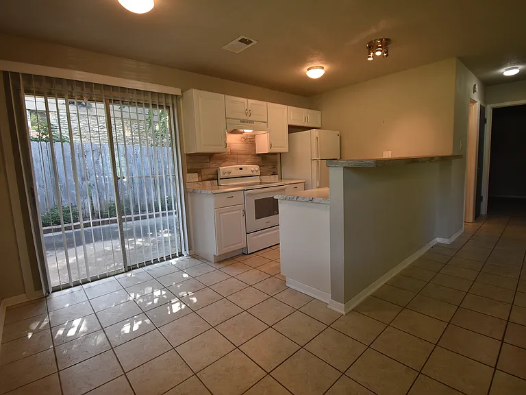 Kitchen features a tiled walk-up bar, new refrigerator, electric stove and dishwasher. Adjacent dining room has a sliding glass door that opens up to a cute patio. To the right there's a hall that leads to the bedrooms and bathroom