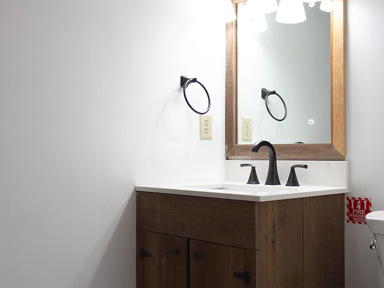 The basement bathroom features the original cedar vanity with a new vanity top, toilet, and LVT flooring...