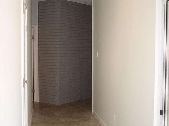 Main entry hallway with tow bedrooms on the left and primary bedroom ahead on the left