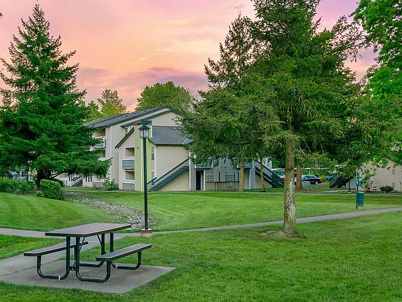 Picnic table and green space with mature trees.