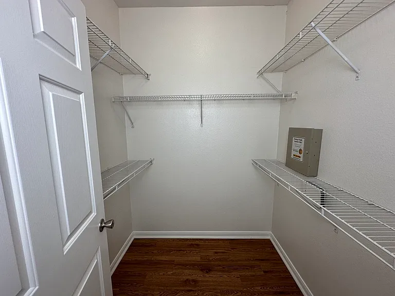 Spacious walk-in closet with ample shelving and wood-style floors, perfect for organized storage. Spacious walk-in closet with ample shelving and wood-style floors, perfect for organized storage.