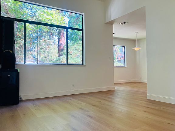 living room with large windows, vaulted ceiling, hard surface flooring, and window unit portable A/C