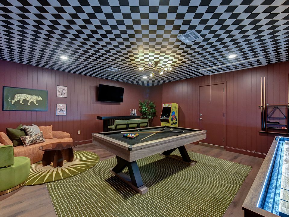 Funky game room with pool table, shuffleboard, dartboard, bar, TV, and retro arcade games