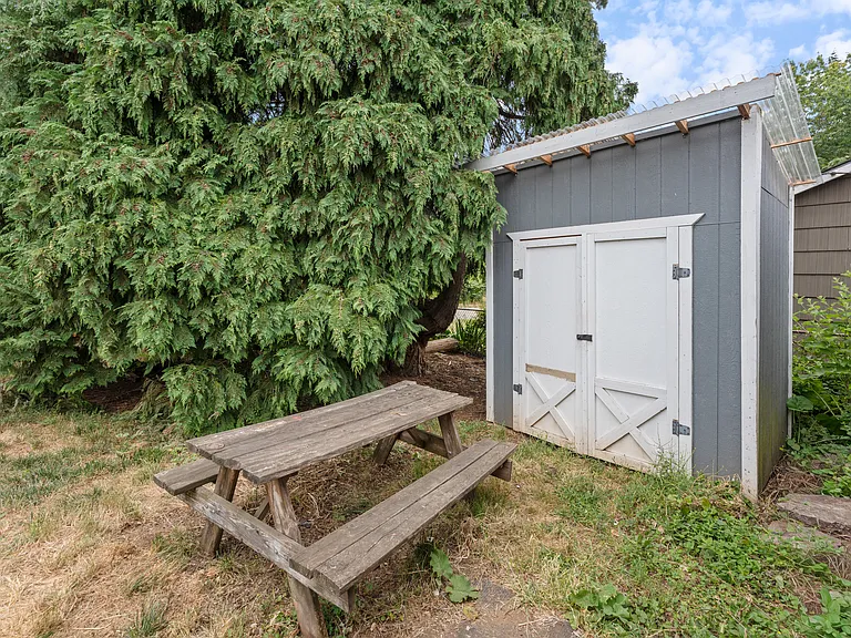 tool shed between garage and large cedar trees