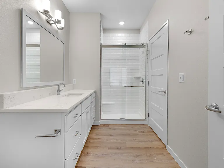 Elegant bathroom featuring a sleek glass shower, spacious vanity with modern fixtures, and warm wood flooring. Elegant bathroom featuring a sleek glass shower, spacious vanity with modern fixtures, and warm wood flooring.