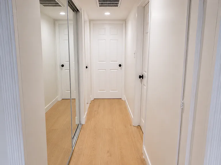 Hallway leading to Bedrooms 2 and 3, the shared bathroom, and a mirrored closet with washer and dryer hookups.