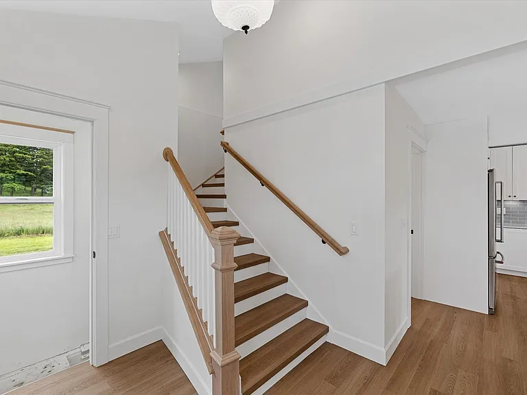 Vaulted ceilings greet you through the back entry. Basement entrance to the left, kitchen/laundry to the right.