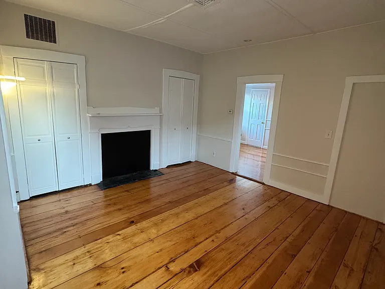 Classic, cozy living room with decorative fireplace and newly refinished hardwood floors. Ample closet space in living room and bedroom.