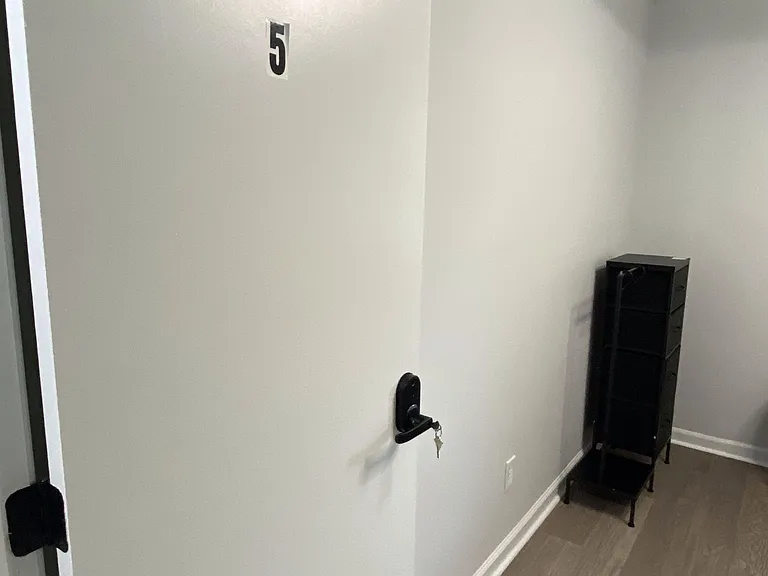 Private, lockable room entry with a clean hallway approach and durable wood-style flooring for easy upkeep.