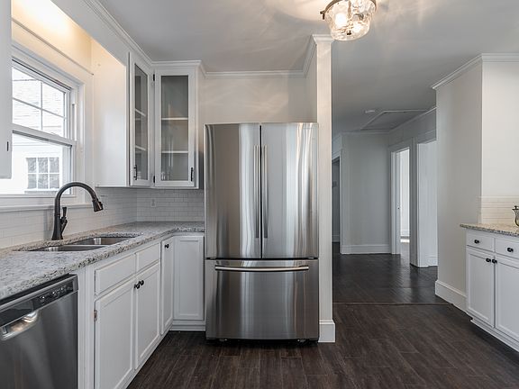 Stainless refrigerator. Kitchen sink is at window looking into backyard.
