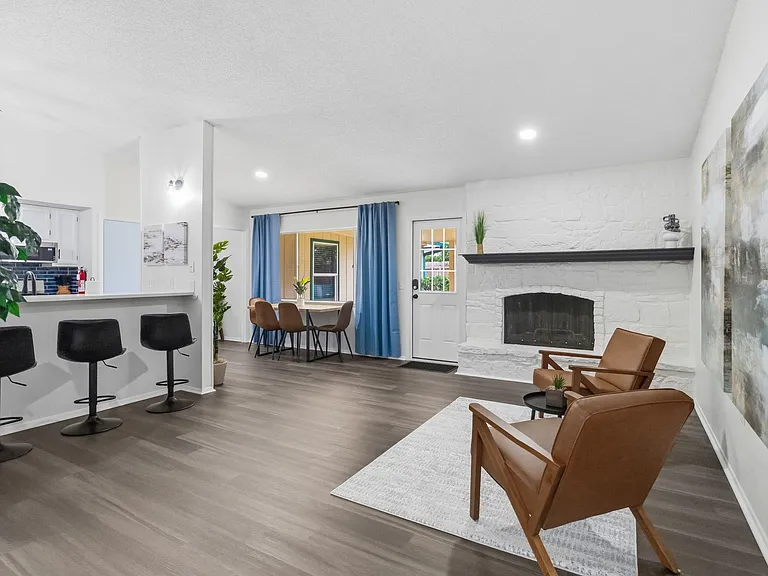Open-concept living area with bar seating, dining space, and a statement fireplace, plus patio access and easy-flow layout.