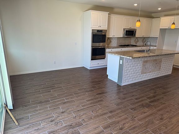 View of open concept dining area and kitchen, which has decent sized island, double oven, range, above range microwave and dishwasher.