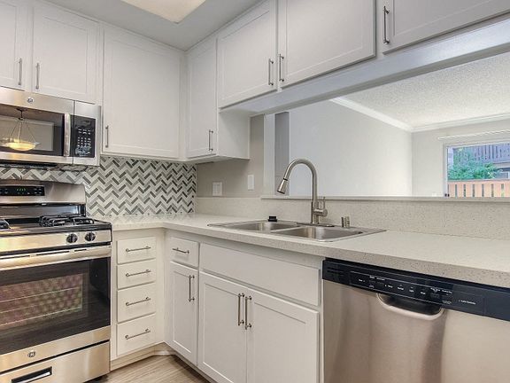 Renovated kitchen with white cabinets, countertops and stainless steel appliances