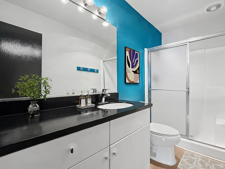 Renovated Package I bath with black laminate countertop, white cabinetry, and updated hard surface flooring