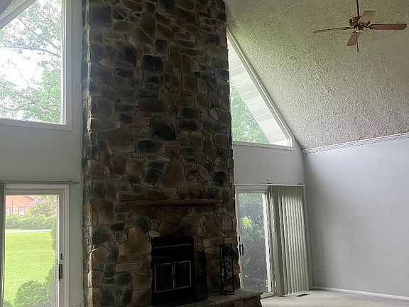 Great room with a two story woodburning fireplace and lovely sunlight.