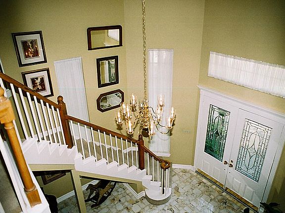 Balcony view of foyer with big-chip marble flooring and suspended chandelier.