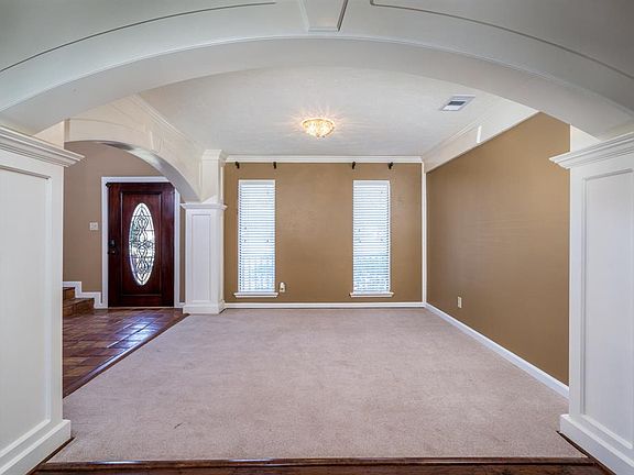 View of the entry and formal dining room with arched doorways, crown molding and wainscoting.