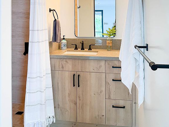 New modern bathroom with travertine floors and shower stall.