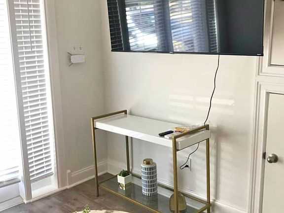 Bright studio with beautiful blinds, window, Smart TV, and decorative coffee table.