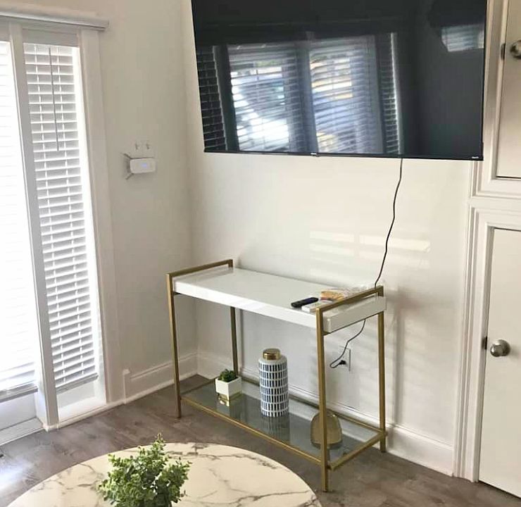 Bright studio with beautiful blinds, window, Smart TV, and decorative coffee table.