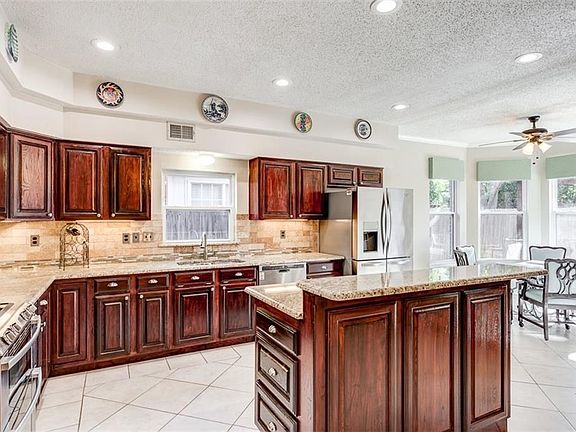 Granite counters shine with under the cabinet lighting. Lots of storage with these custom built cabinets. Tumbled subway stone back splash. Combination island-breakfast bar. Under-mount stainless steel sink. Stainless steel appliances.