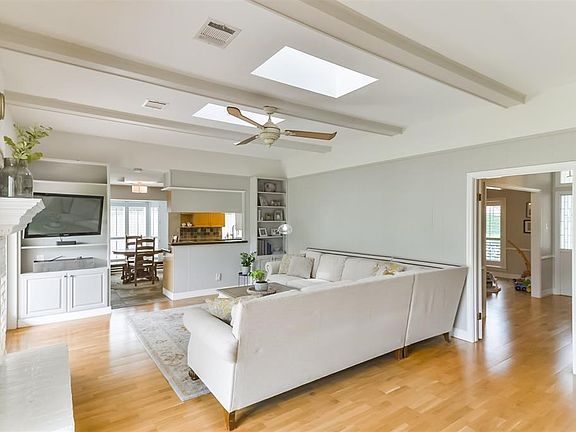 Family room is open to kitchen, features painted beams, built ins, ceiling fan, and substantial gas log painted brick fire place.