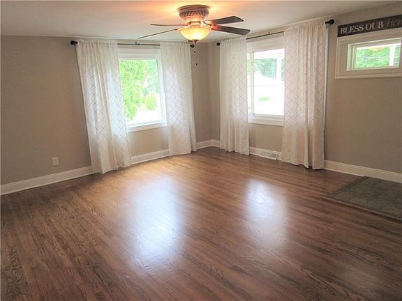 Living room features a 4 x 5 ft ceramic tile entry, beautifully refinished hardwood floors, two picture windows, and a ceiling fan with a light.