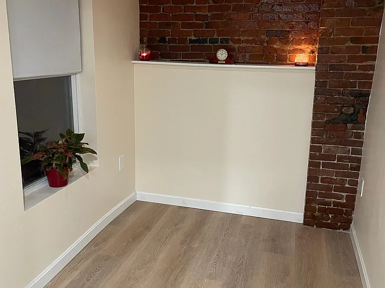 Bedroom has an exposed brick wall with custom build shelf.