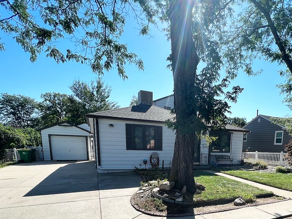 Grassy front yard with deep driveway and large, old trees.