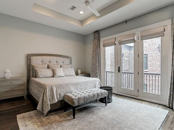 This elegant master suite has reclaimed hardwood floors, coffered ceiling with recessed lighting, and French doors leading to a private balcony.