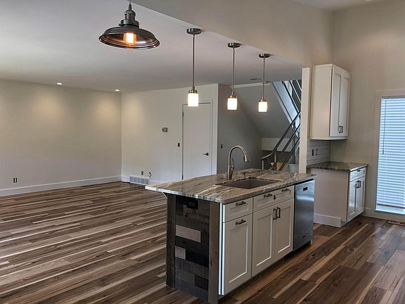 Dining area view of kitchen island with stairway entrance in background.