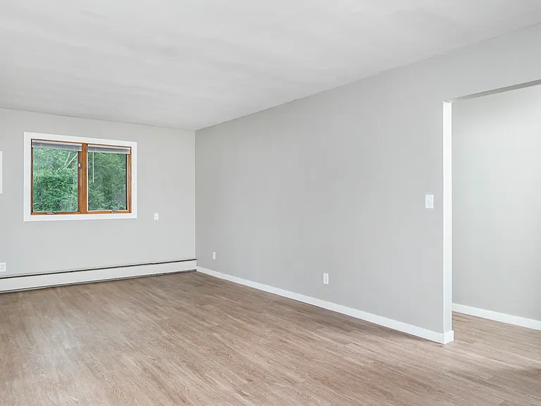 Bright and airy living space with sleek hardwood floors and a large window showcasing lush greenery. Bright and airy living space with sleek hardwood floors and a large window showcasing lush greenery.