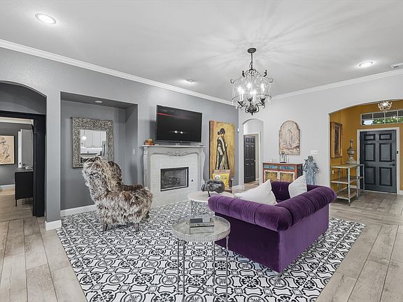 Living area featuring arched walkways, custom flooring, crown molding, a custom tile fireplace, light wood-style flooring, and recessed lighting