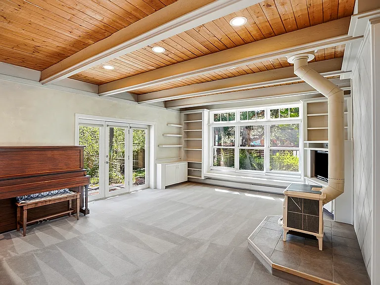 A stunning gathering space featuring dramatic wood beams, expansive windows, French doors, and a wood stove_the heart of this distinctive Boulder home.