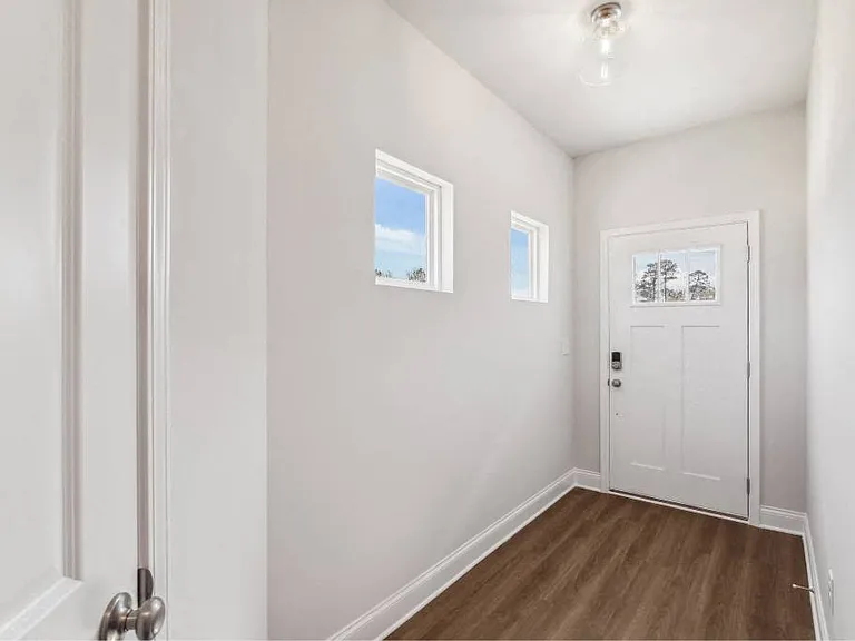 The entrance to the Carlisle home featuring rich hardwood-style flooring and crisp white walls.