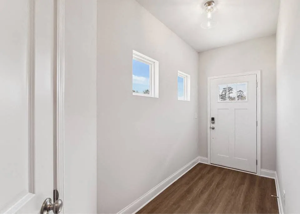 The entrance to the Carlisle home featuring rich hardwood-style flooring and crisp white walls.
