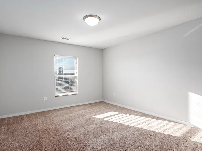 Bright, spacious room with soft carpet flooring and a large window, allowing natural light to fill the space. Bright, spacious room with soft carpet flooring and a large window, allowing natural light to fill the space.