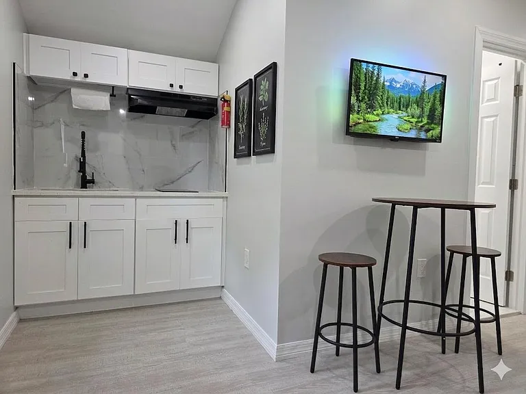 Updated kitchenette with shaker cabinetry, marble-look backsplash, and a bar-height dining nook for quick meals.