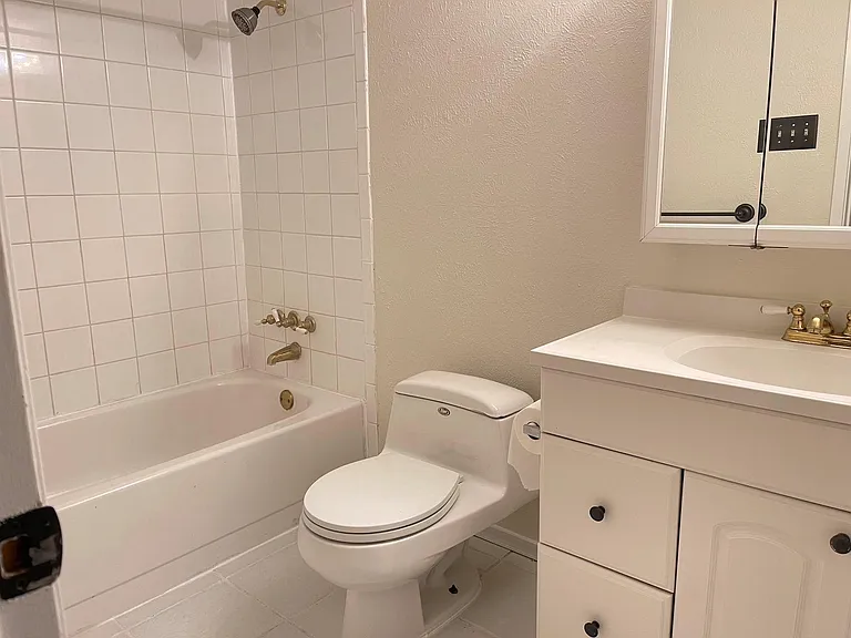 Full bathroom with tile floors, toilet, oversized vanity, and tiled shower / bath