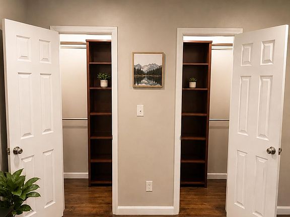 Bedroom storage area featuring two closets with built-in shelving and hanging rods, plus hardwood flooring and overhead light