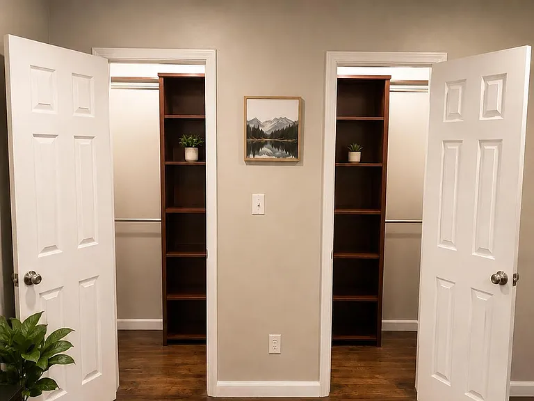 Bedroom storage area featuring two closets with built-in shelving and hanging rods, plus hardwood flooring and overhead light