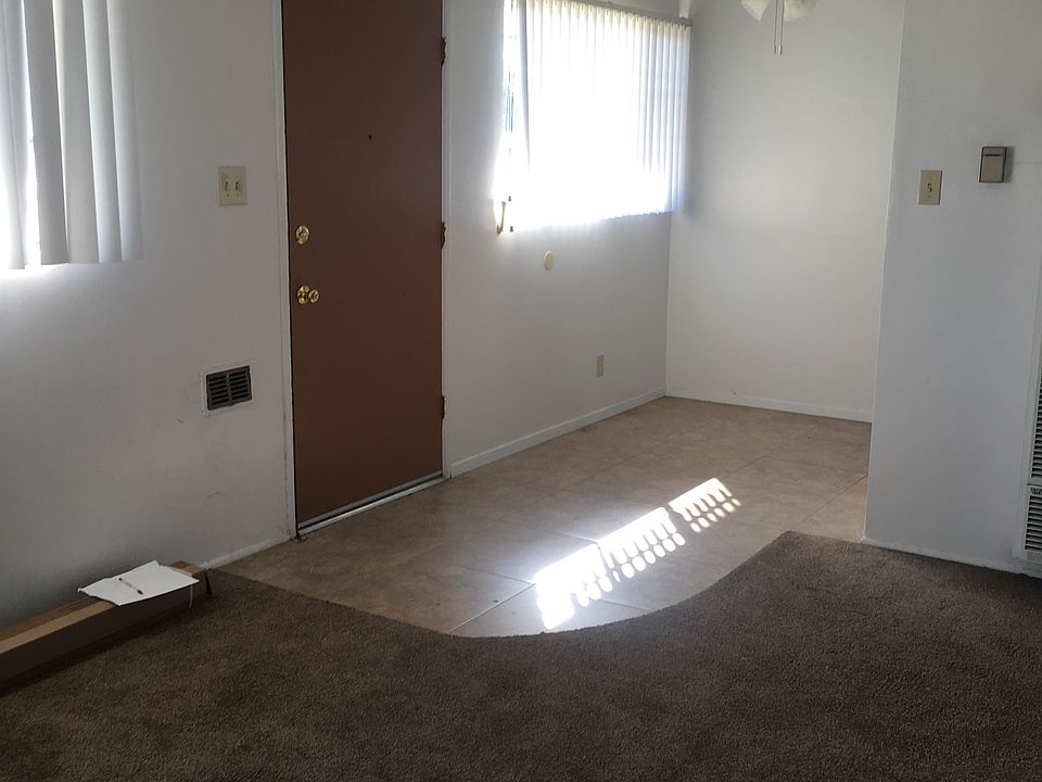 Front door opens to carpeted living room and tiled dining room with overhead fan. This picture is not the actual unit for rent but all units have the same floor plan. The carpeting in the unit for rent is dark blue not brown (see other photos shown).