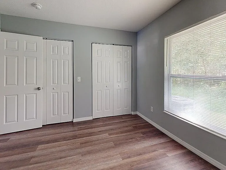 Bright room with large window, sleek wooden flooring, and ample closet space, ideal for a cozy bedroom or home office.