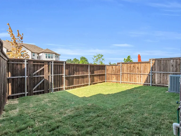 Fenced backyard featuring a grassy lawn, wood privacy fencing, and a side gate