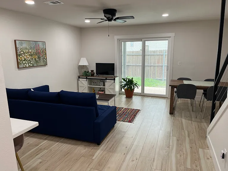 Furnished living room includes sofa, coffee table, and console for a tv, dining space includes table and four chairs, plus two pub height chairs at the counter. Decor items included.