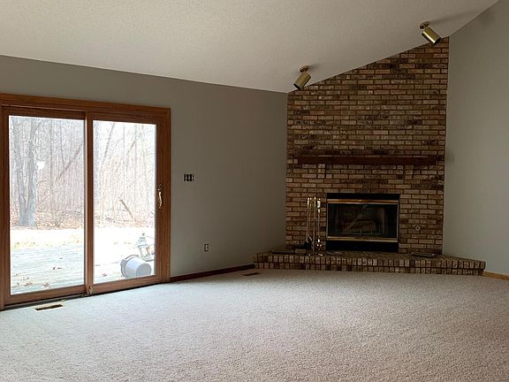 Main floor- carpeted living room w ceiling fan, fire place, and patio doors