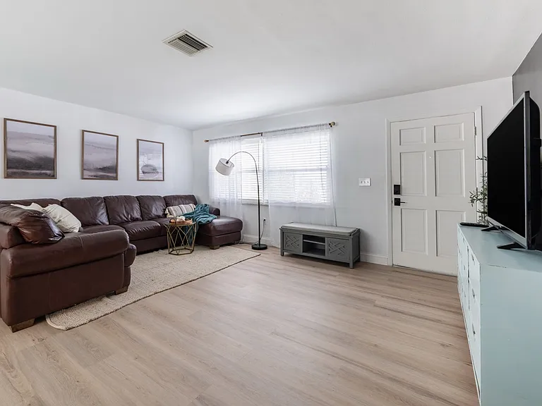 The home's front door opens into the living room equipped with a very large, very comfortable leather couch and smart TV.