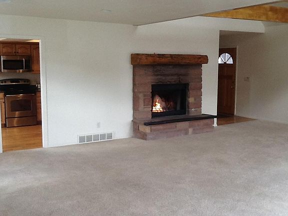 Stone living room fireplace with kitchen entry. Room for dining area in living room.