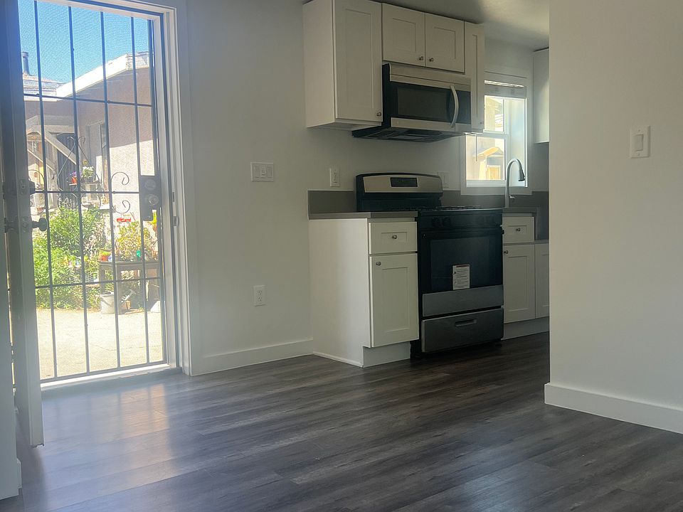 Living room facing front door with kitchen off to the side
